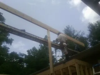 Carpenter setting a ridge beam over a new addition frame — Ice Dam Removal by Roofing Brothers in Lissie