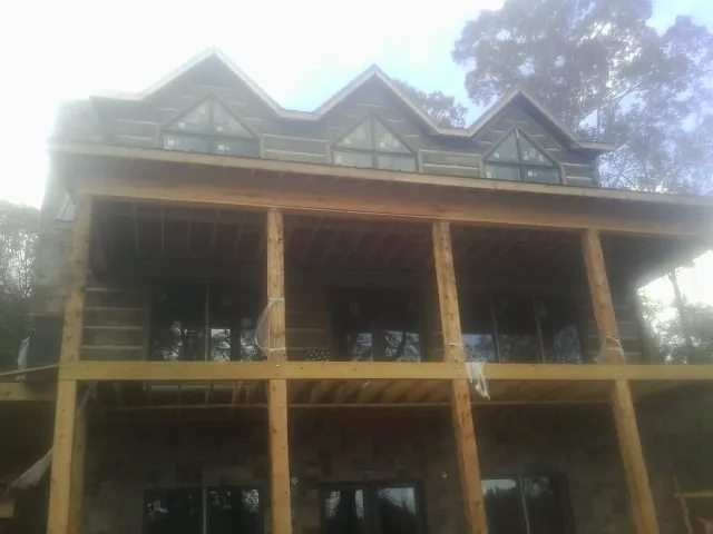 Dormers and porch framing on a large log home under construction — Roof Coating work by our crew in Lissie