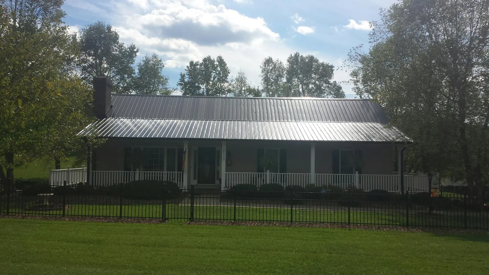 Gray metal roof on a brick ranch with a full width front porch — Gutter Guard Installation work by our crew in Lissie