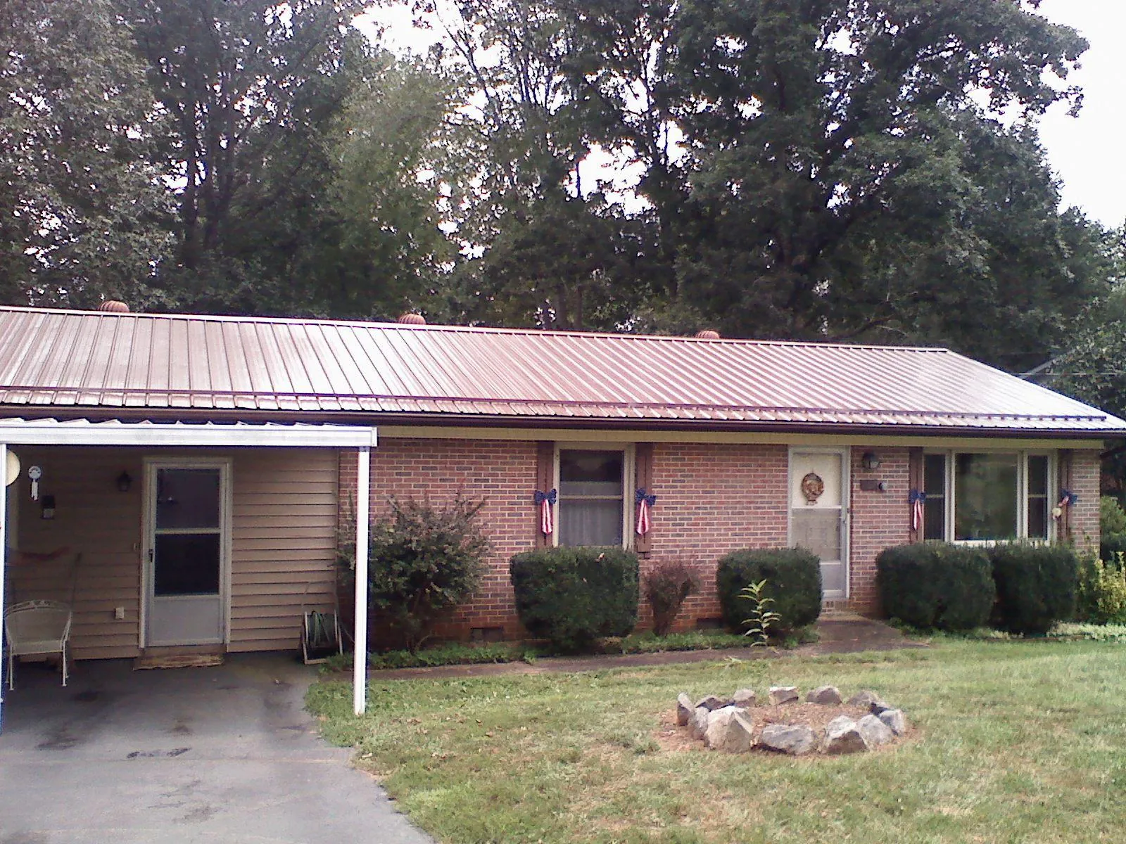 Bronze metal roof and carport on a brick ranch home — Roof Repair work by our crew in Lissie