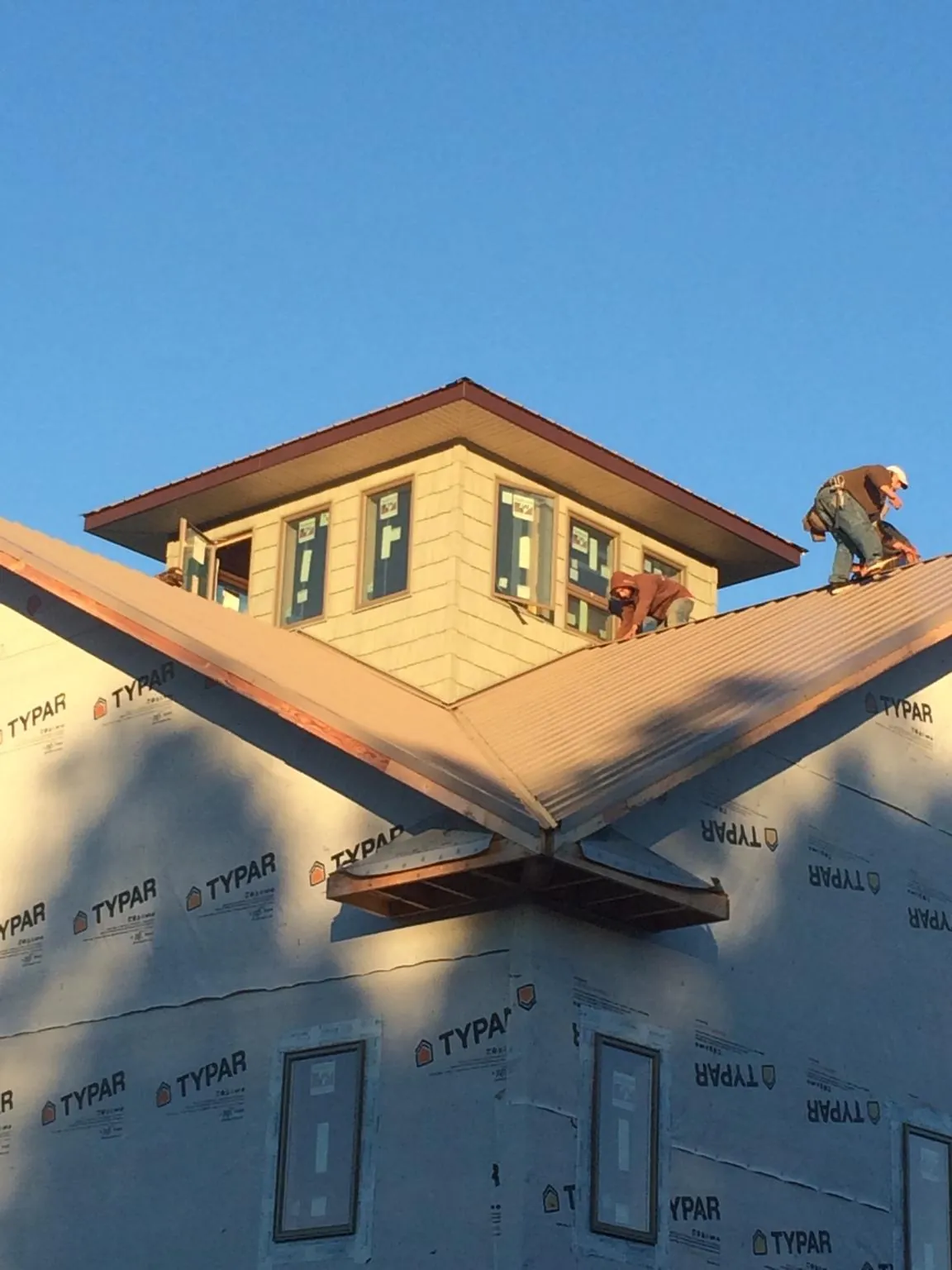 Roofers working around a rooftop cupola on a new metal roof at sunset — Roof Waterproofing in Lissie by Roofing Brothers